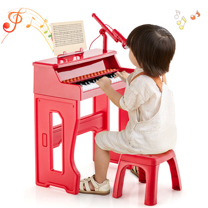 A child sits on the red stool playing the red electronic piano keyboard with microphone