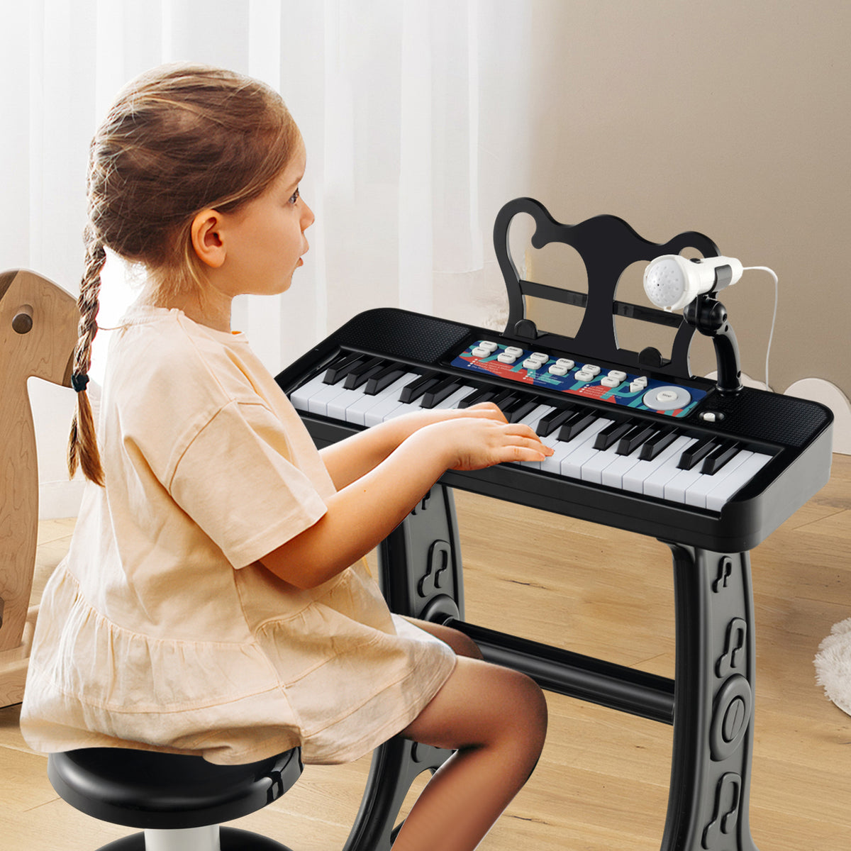 A young girl playing the black kids electric piano keyboard with microphone and stool