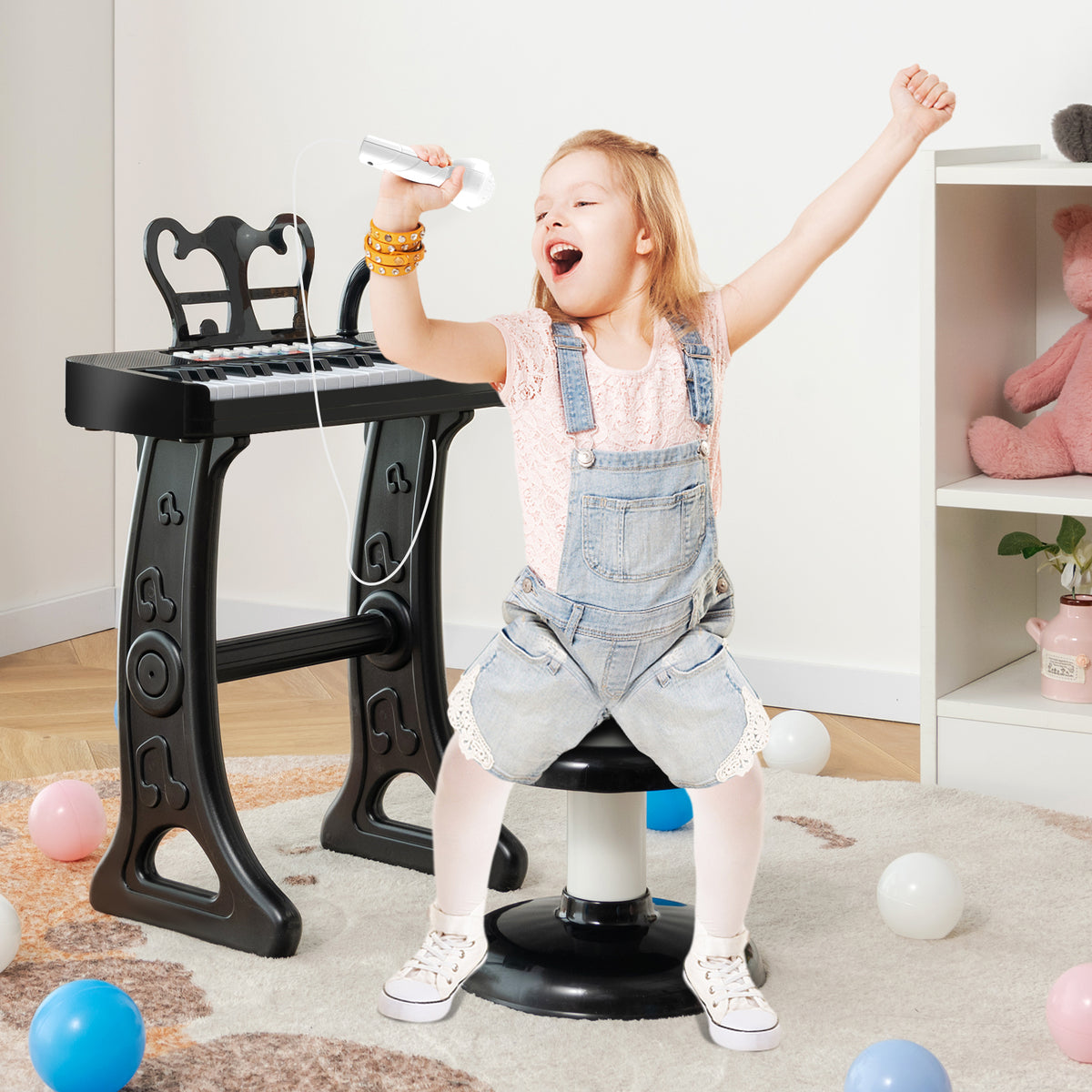 A happy girl singing into the microphone of the black kids electric piano keyboard