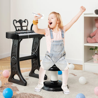 A happy girl singing into the microphone of the black kids electric piano keyboard