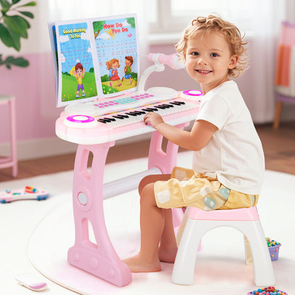 A young child sitting on the stool playing the pink electronic piano