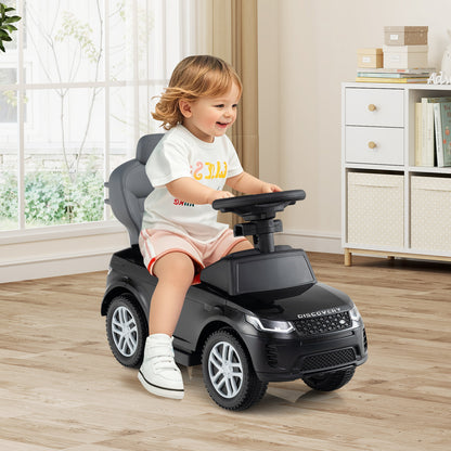 A toddler happily rides the black push and pedal ride on toy indoors