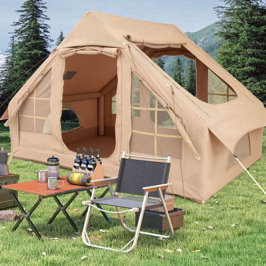 The beige inflatable tent set up on a grassy field with a folding table and camping chair