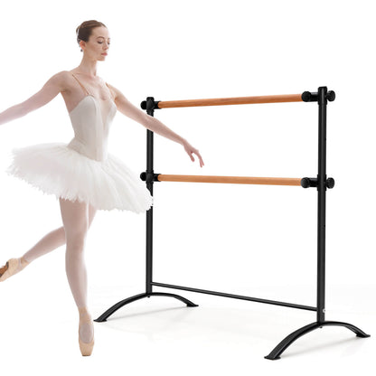 A ballet barre with two wooden bars and black metal frame, used by a dancer
