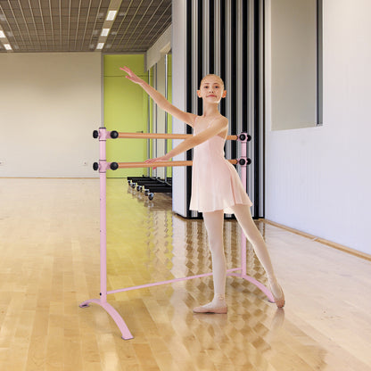 A young ballet dancer practices at the pink barre in a dance studio