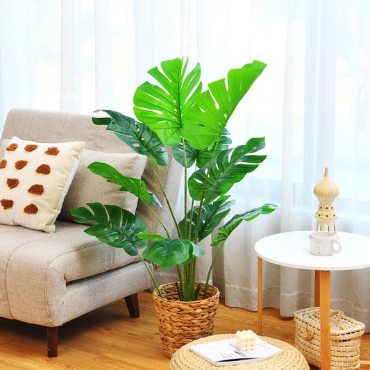 The faux plant is placed in a woven basket next to a sofa and a round table