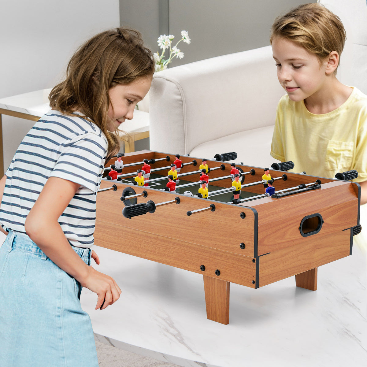 The game table set being used by two children for a foosball match on a white table