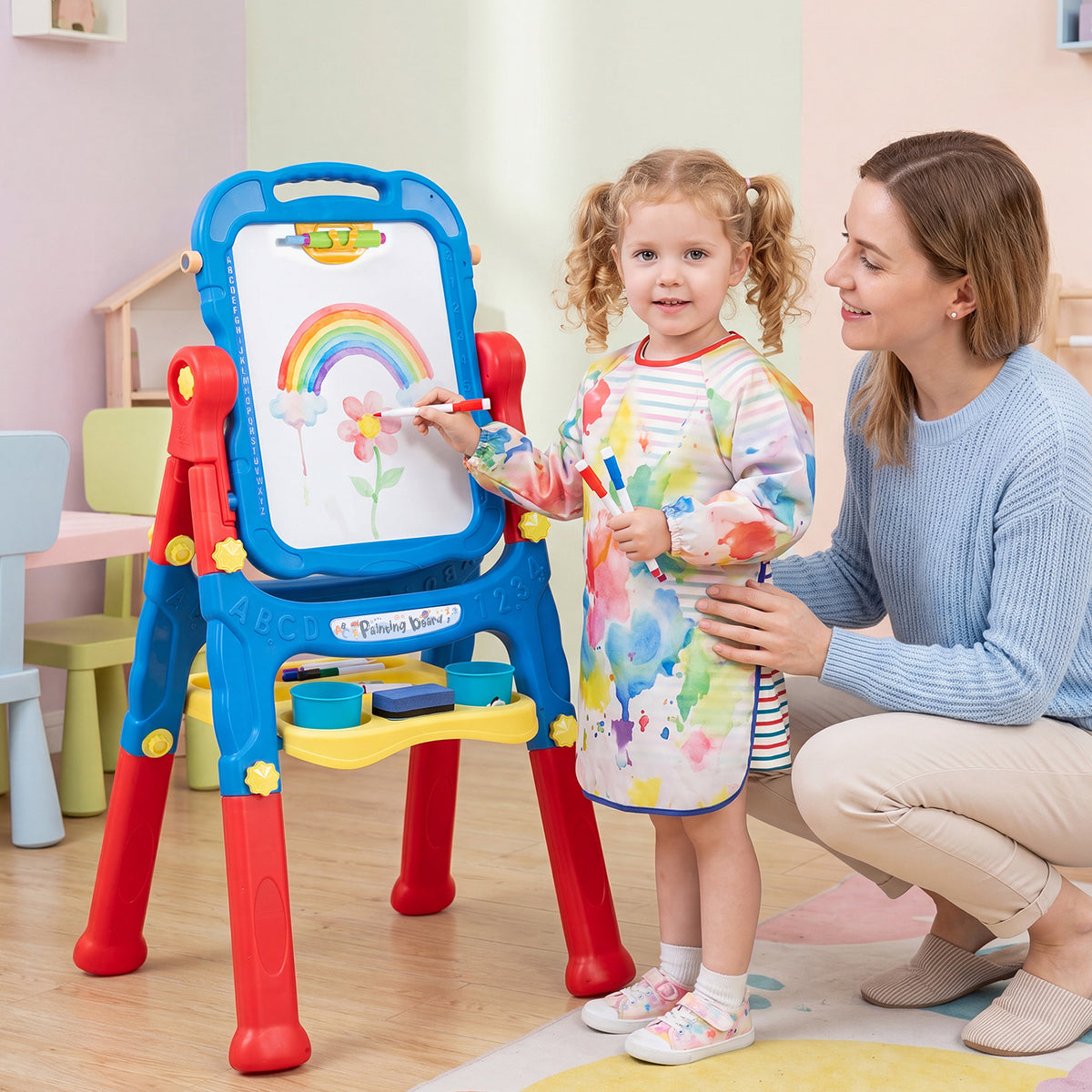 The art easel being used by a young girl with her mother in a bright playroom setting