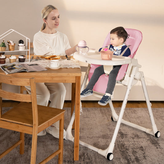 Woman feeding a baby in the pink high chair at a wooden dining table