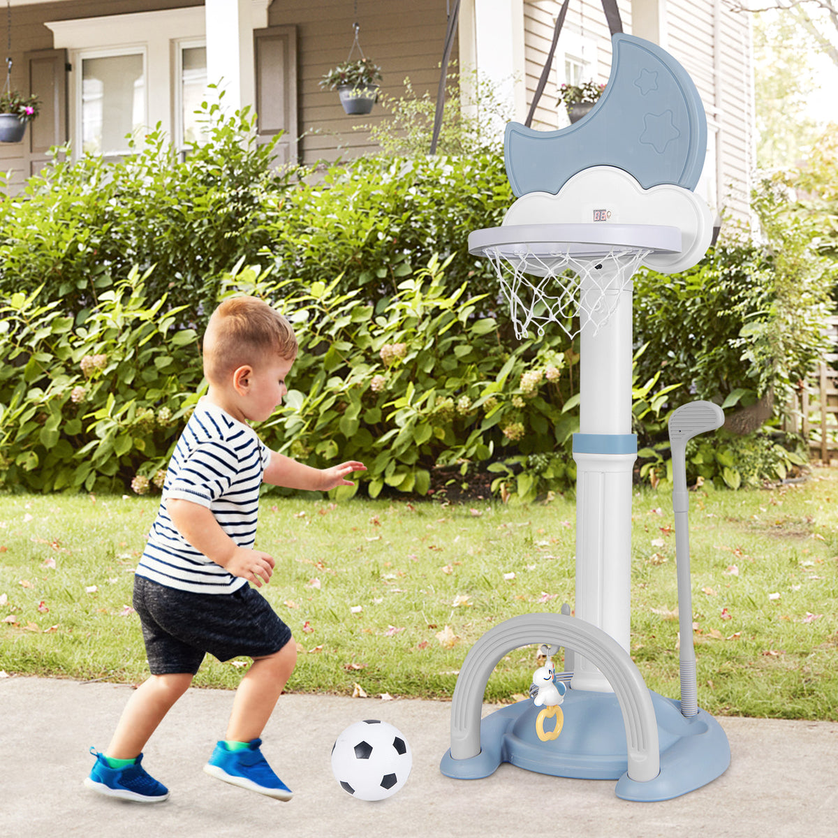The blue kids basketball hoop with adjustable height, shown outdoors with a boy playing soccer