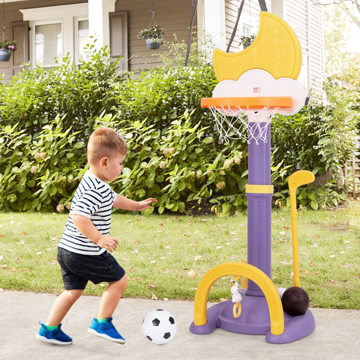 A young boy plays with the kids basketball hoop toy sports set outdoors on a patio