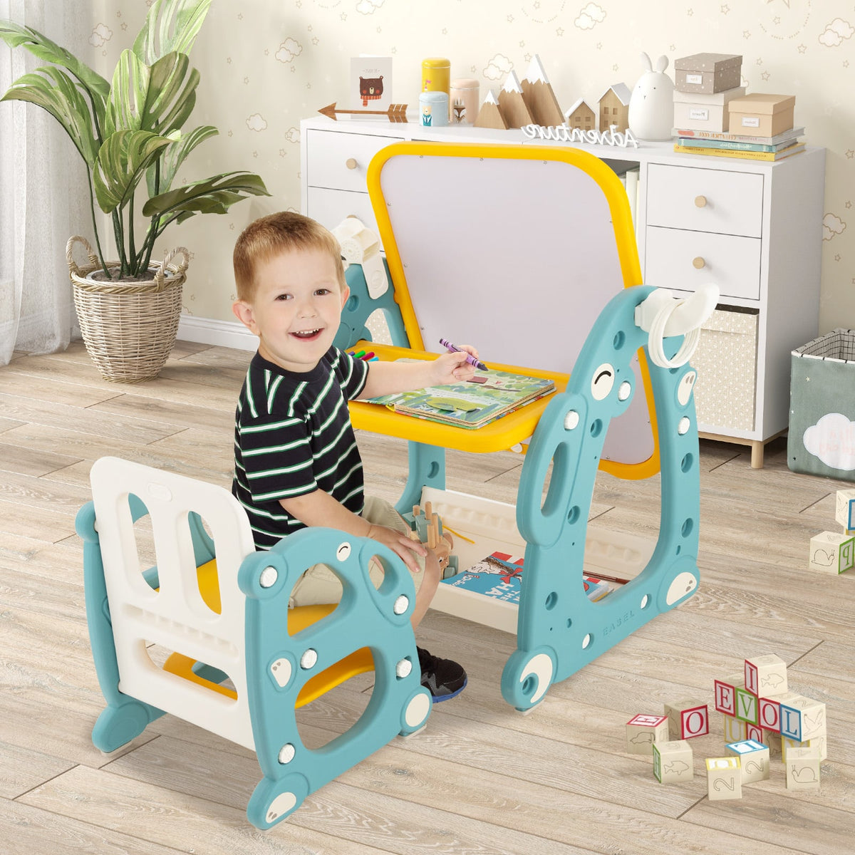 A young boy happily drawing at the kids table and chair set in a bright room