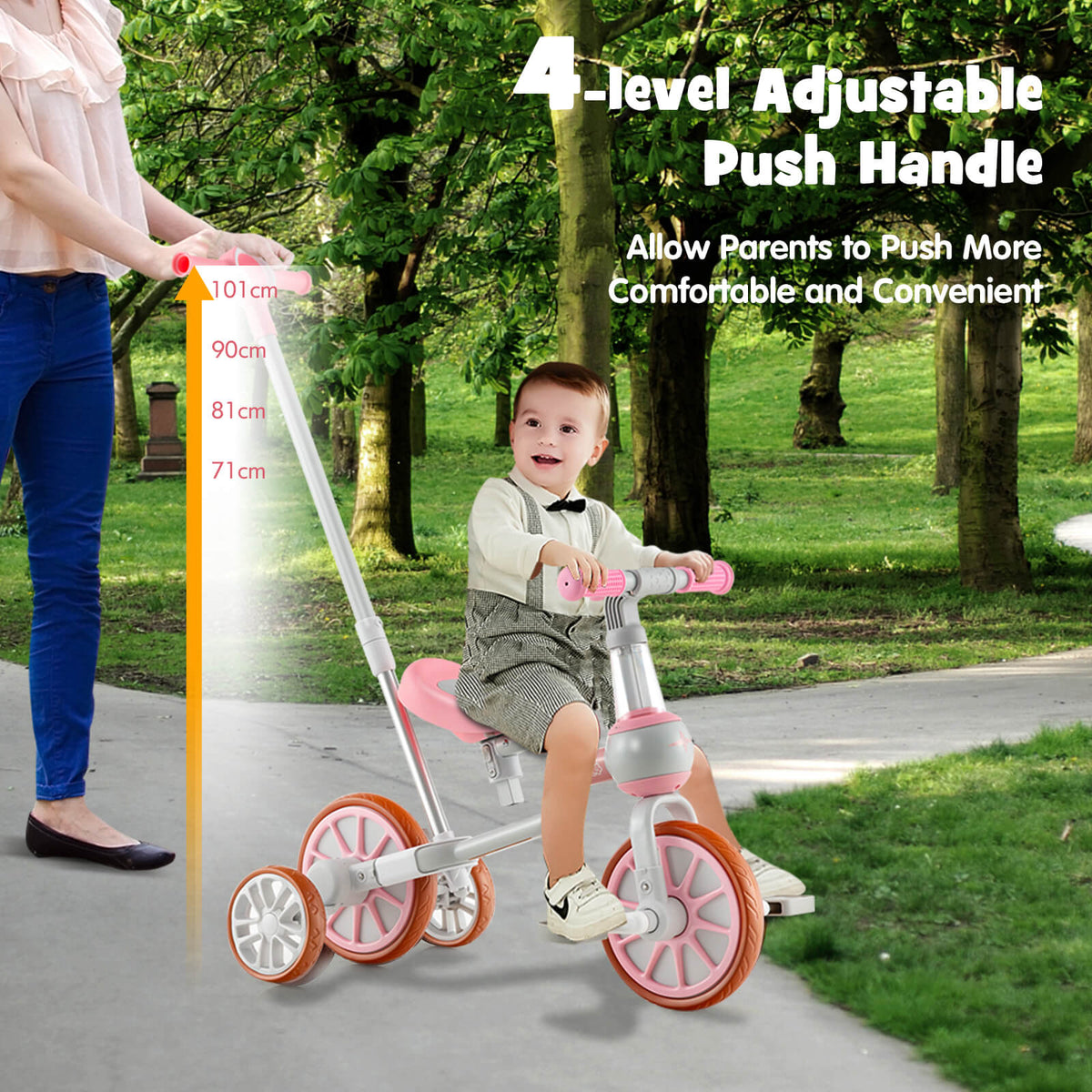 A parent pushes the pink training trike with a child on it using the adjustable handle