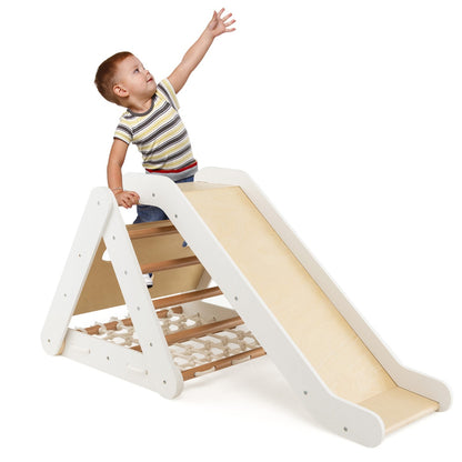 A young boy reaches up towards the climbing net on the wooden climbing frame