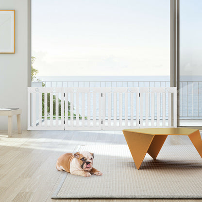 A bulldog puppy lies on a rug in front of the white pet gate, which is set up on a balcony with a sea view