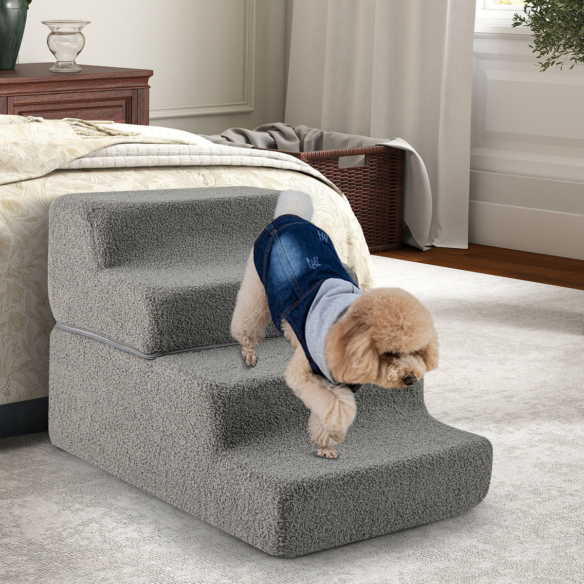 Dog wearing a denim jacket resting on grey foam dog stairs next to a bed