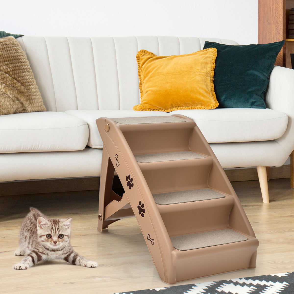 A four-step pet stair unit is placed next to a sofa, with a kitten looking at it