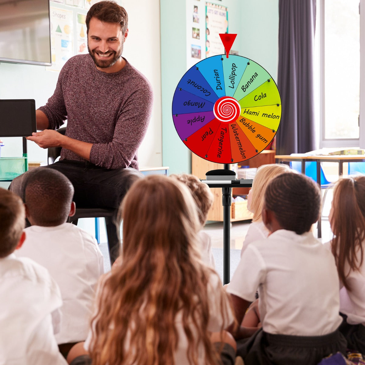 The prize wheel being used by a teacher in a classroom setting with children watching