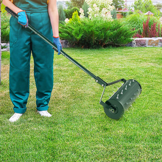 A person in green work clothes using the lawn care tool on a grassy garden lawn