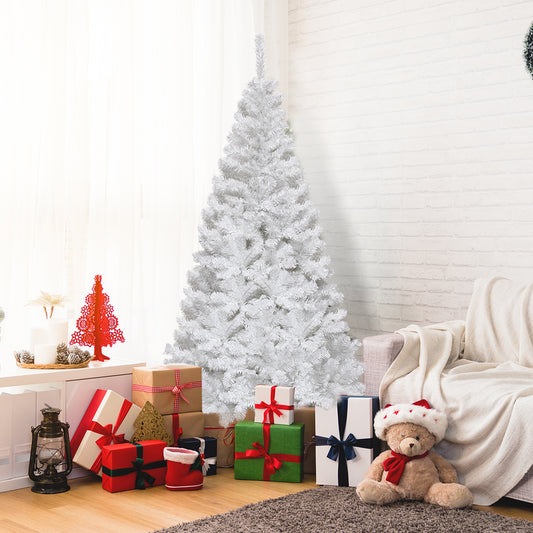The artificial tree placed in a living room next to a sofa with wrapped gifts and a teddy bear