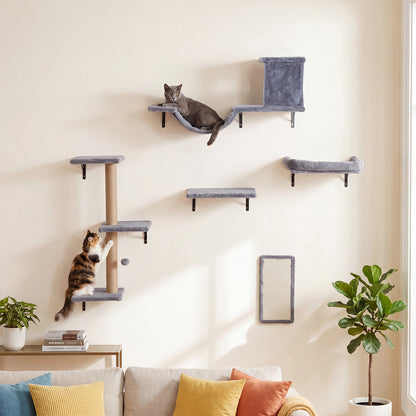 The cat furniture mounted on a living room wall with two cats playing and resting on the platforms