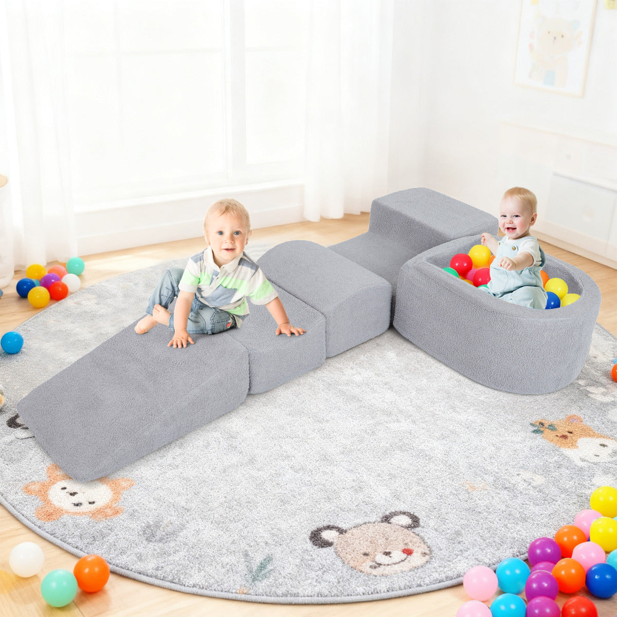 The soft play set with two babies playing on the grey foam blocks and balls