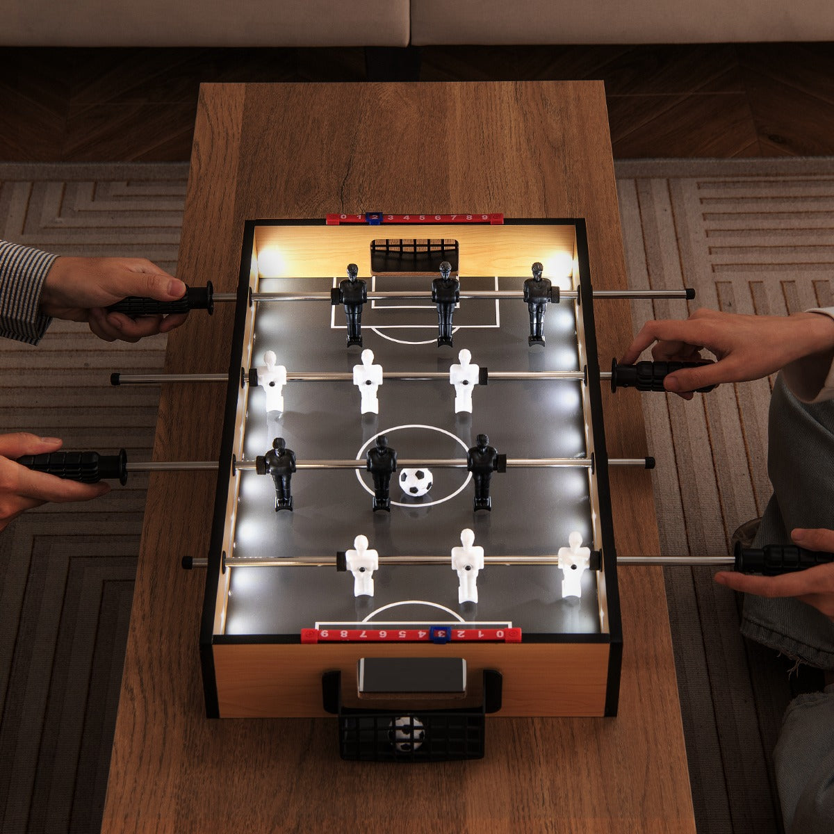 Close up of the foosball table with LED lights and two players hands on the handles
