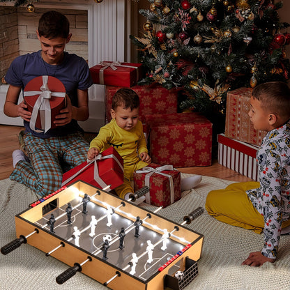 Family playing a foosball game with LED lights around a Christmas tree