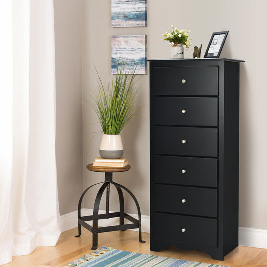 The black dresser cabinet is shown in a bedroom setting next to a small side table and plant