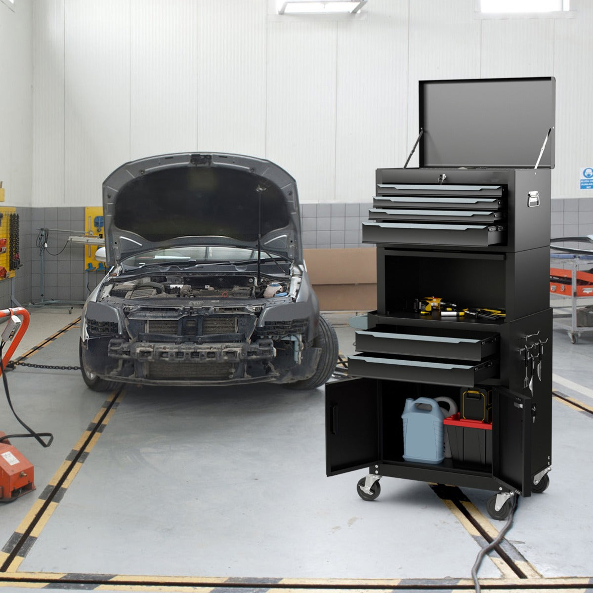 The tool chest placed in a car repair garage with the top lid and bottom cabinet doors open