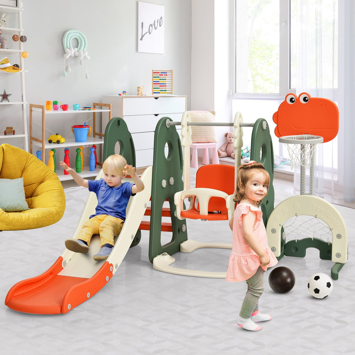 Two toddlers are playing on the orange and green kids slide and swing set indoors