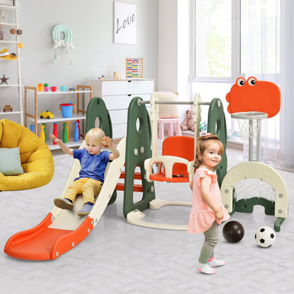 Two toddlers are playing on the orange and green kids slide and swing set indoors