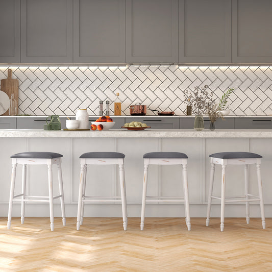 The bar stools arranged in a row along a modern kitchen island with a herringbone tiled wall