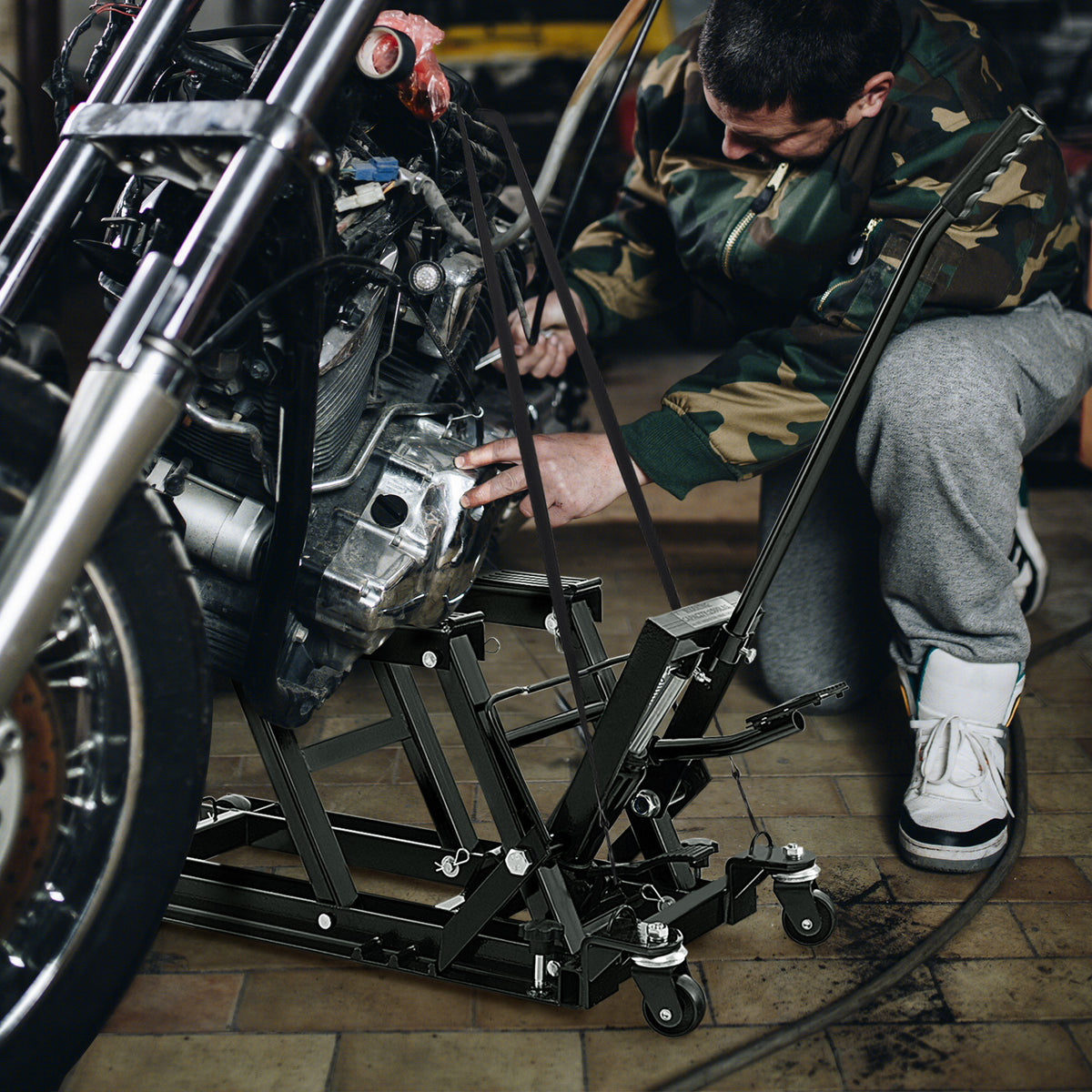 Mechanic working on a motorcycle raised by a black lift jack