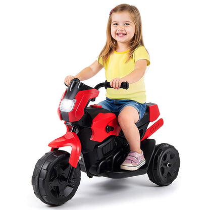 A young boy sits on the red kids electric motorbike outdoors