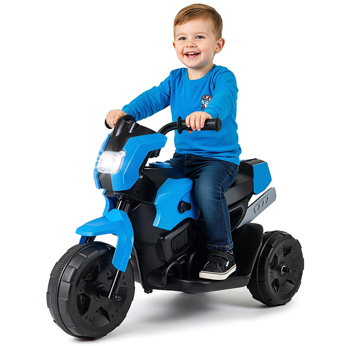 A happy child sitting on the kids electric motorbike against a white background