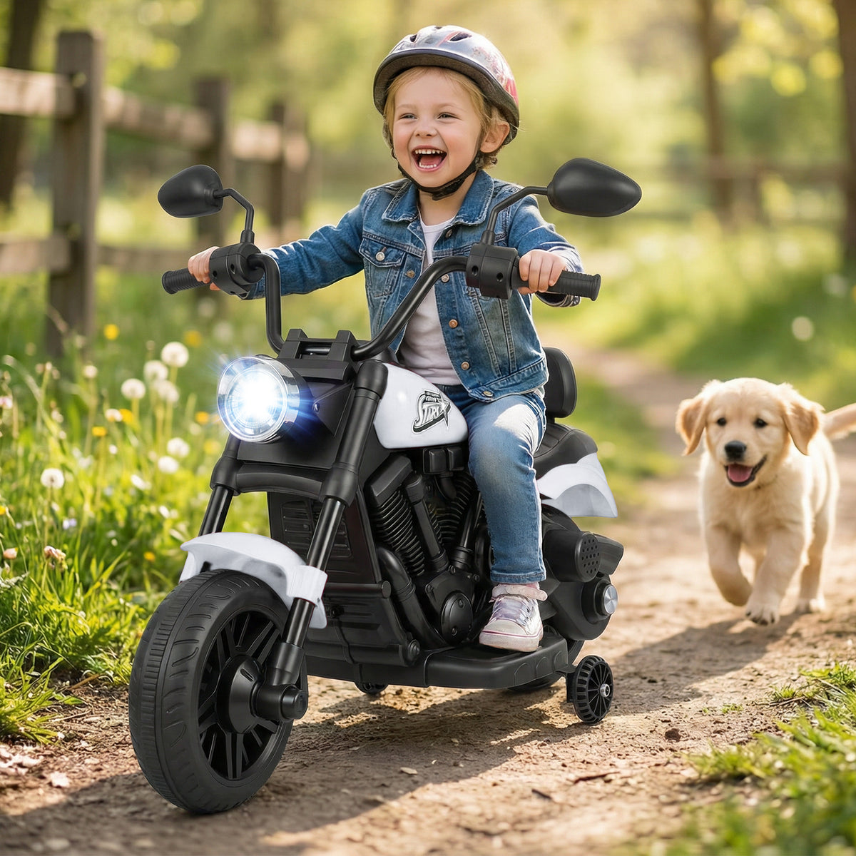 A young child wearing a helmet rides the kids electric motorbike outdoors with a puppy running alongside