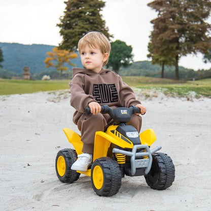 Young boy riding the yellow kids electric quad car outdoors on a sandy track