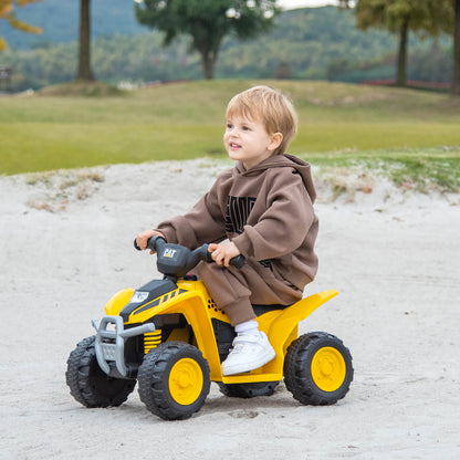 Young boy smiling while riding the yellow kids electric quad car outdoors