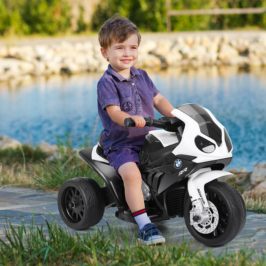 A young boy happily rides a black and white kids electric motorbike outdoors