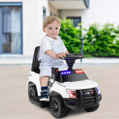 A young child sits in the kids electric police car, holding the steering wheel