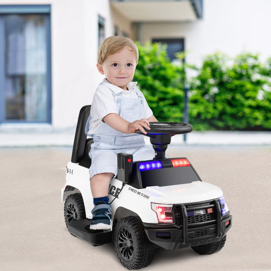 A young child sits in the kids electric police car, holding the steering wheel