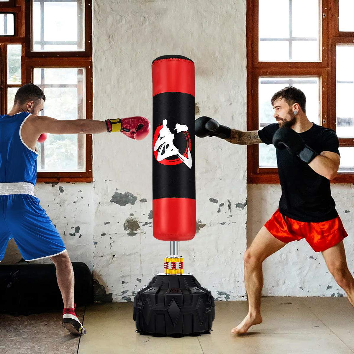 Two men boxing around the freestanding punching bag in a room