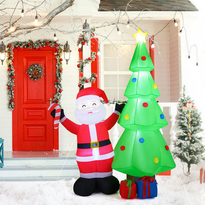 The inflatable Santa and Christmas tree decoration placed on a snowy path in front of a red-doored house entrance