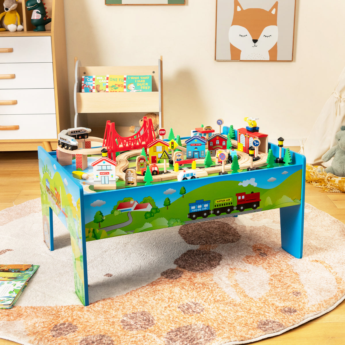 The colourful wooden activity playset with train tracks and buildings, set up on a rug