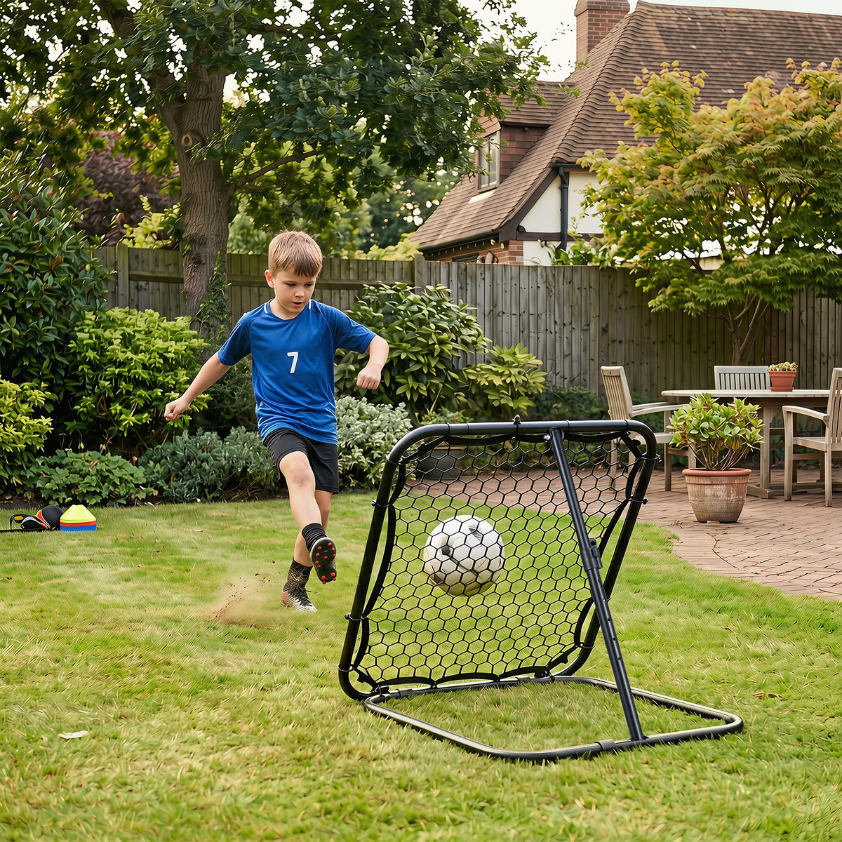 Child plays football using the rebounder in a grassy garden setting