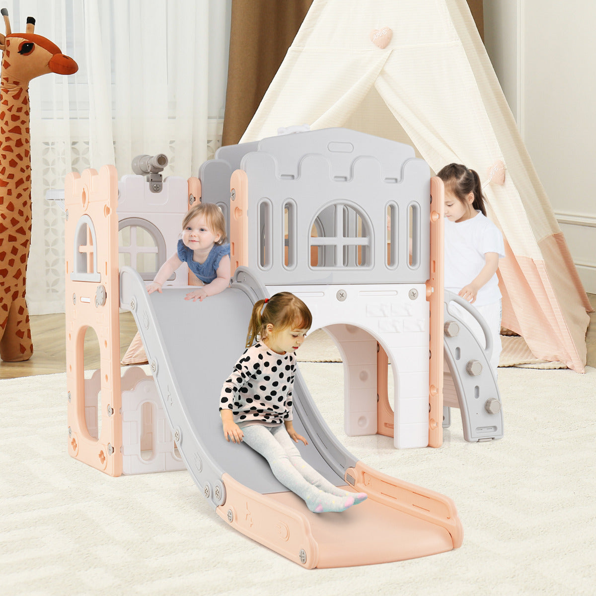 The kids slide being used by two children in a bedroom with a teepee tent and giraffe toy