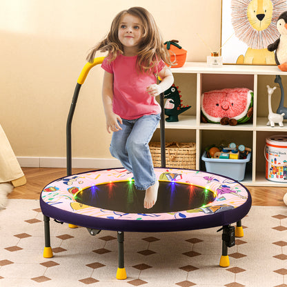 This pink mini trampoline with musical notes and LED lights is set up in a child's bedroom with toys on shelves behind