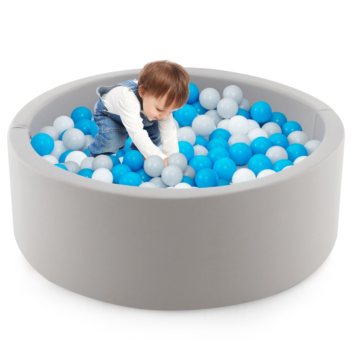A young child playing in the soft play set with blue, white and grey balls