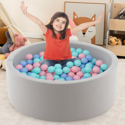 A young girl sitting inside the soft play set with her arms raised in joy
